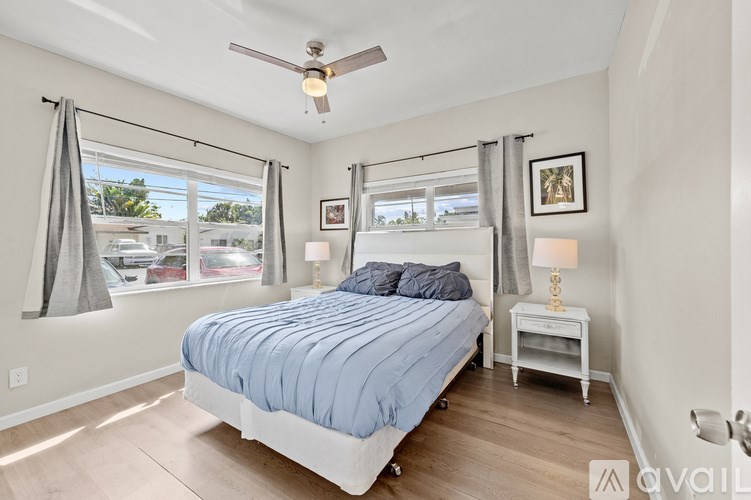 A bedroom with a bed, nightstand, and window.