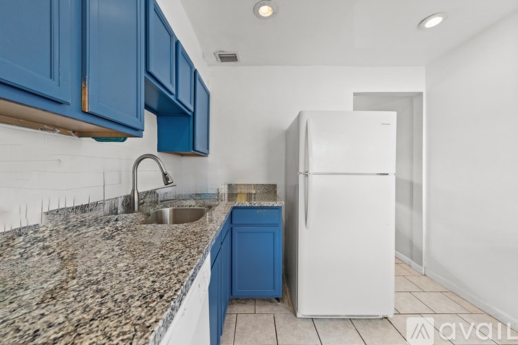 A kitchen with blue cabinets and a white refrigerator.