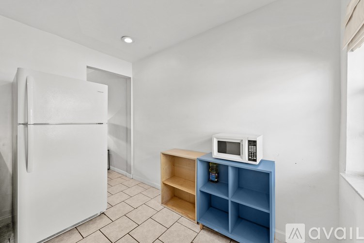 A white refrigerator is in a kitchen with a blue shelf and a microwave on it.