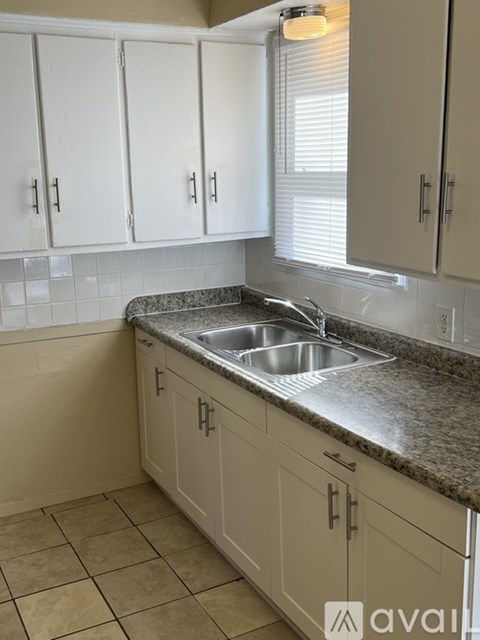 A kitchen with white cabinets and a granite countertop.