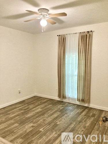 A room with a ceiling fan and a window with curtains.