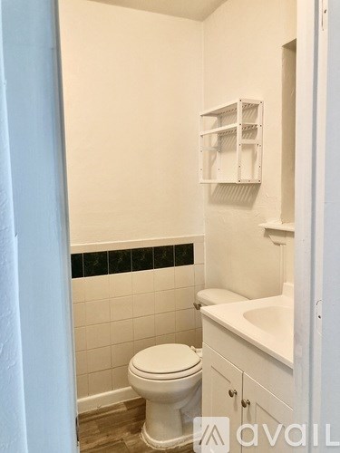 A white toilet sits in a bathroom next to a white sink.