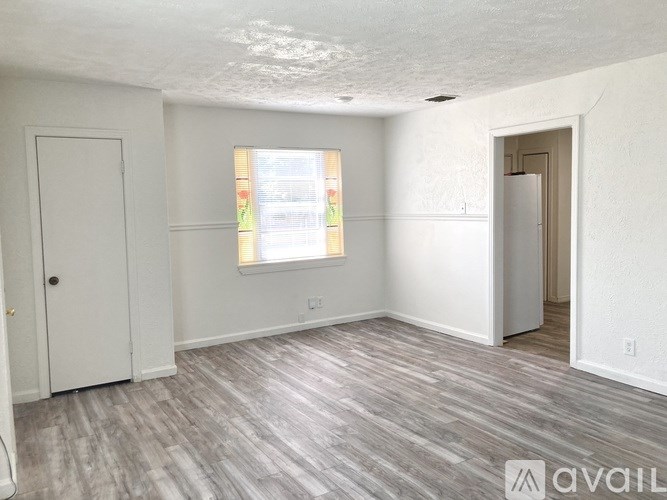 A room with a wooden floor and a window with blinds.