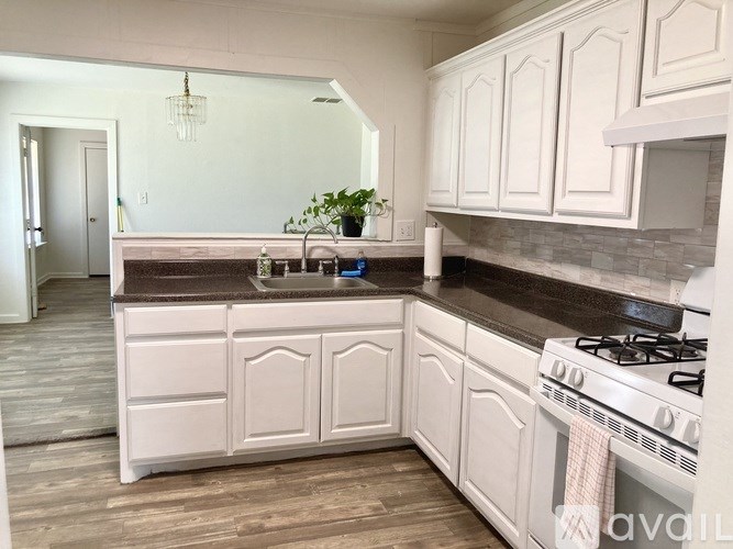 A kitchen with white cabinets and a wooden floor.