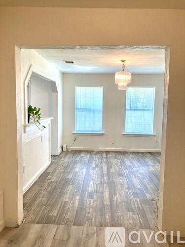 A room with wooden floors and two windows.