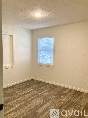 A room with wooden flooring and a window with blinds.