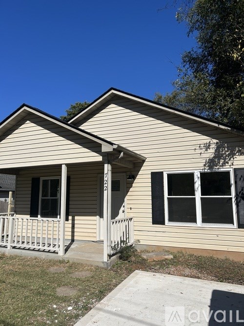 A beige house with a porch and a window with a black frame.