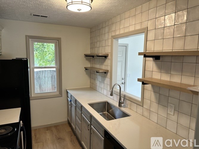 A kitchen with a black refrigerator and white countertops.