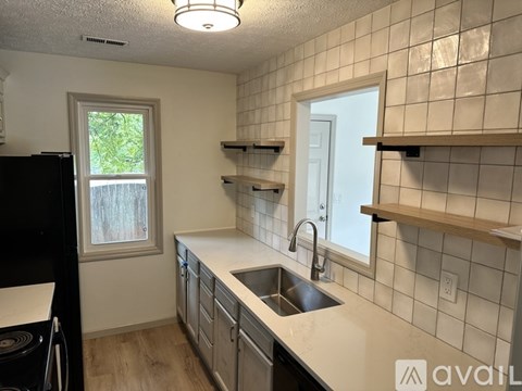 A kitchen with a black refrigerator and white countertops.