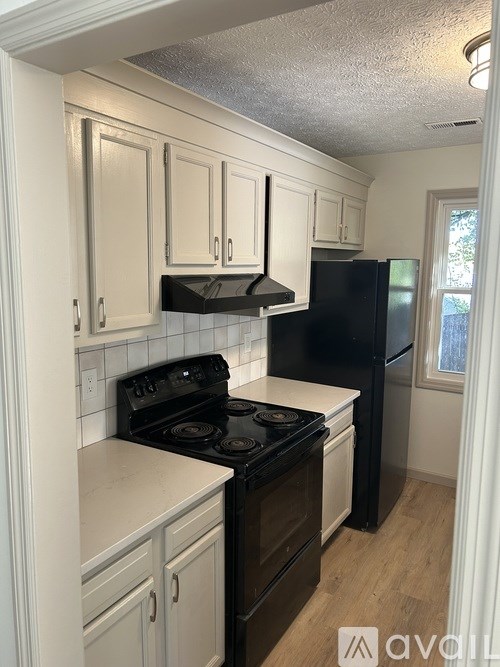 A kitchen with black appliances and white cabinets.
