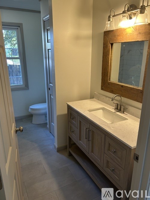 A bathroom with a toilet, sink, and mirror.