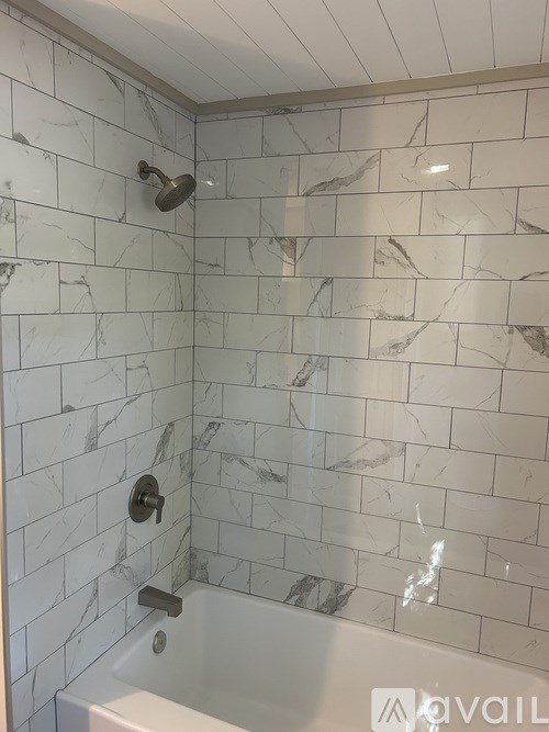 A white bathtub with a shower head and a faucet.