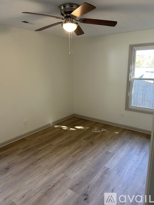 A room with a ceiling fan and wooden flooring.