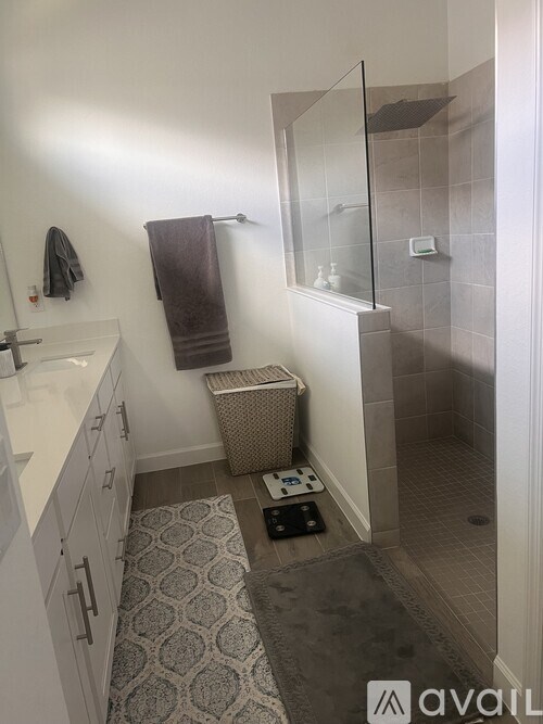 A bathroom with a white sink, a towel, and a glass shower door.