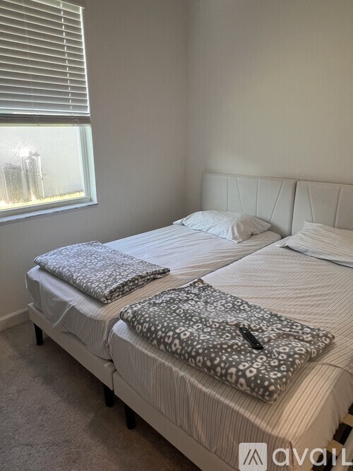 Two beds with pillows in a room with a window.