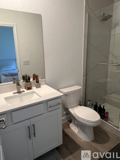A bathroom with a toilet, sink, and mirror.
