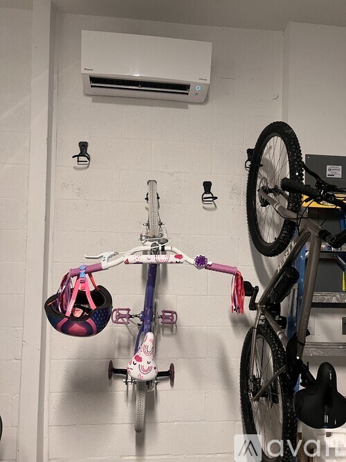 A bicycle with a pink and white frame is hanging on a wall.