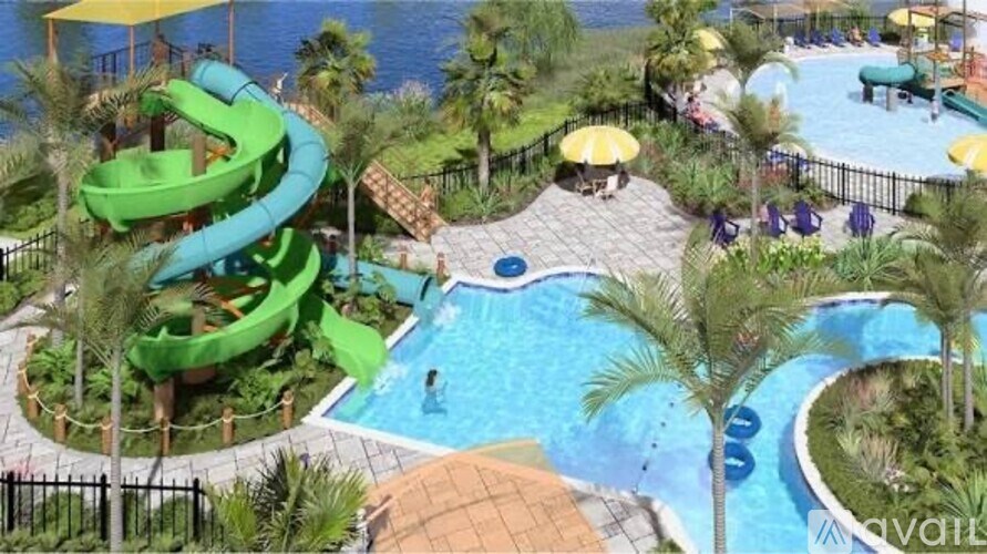 A water slide in a pool surrounded by palm trees.
