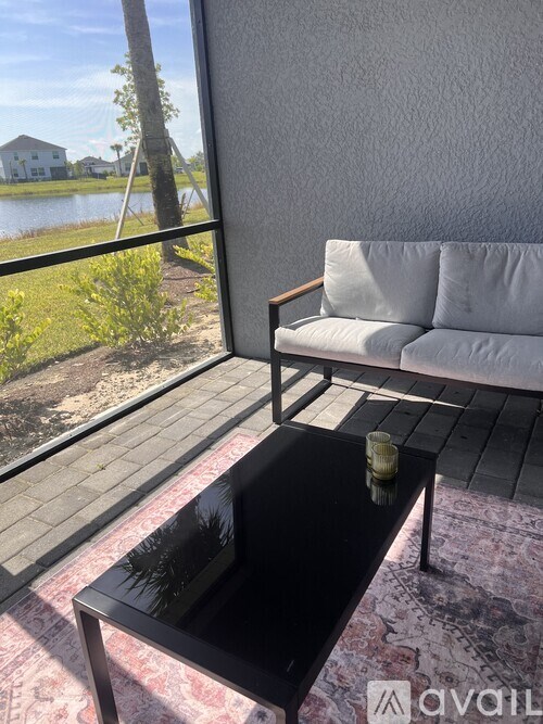 A black coffee table sits on a rug in front of a white couch.