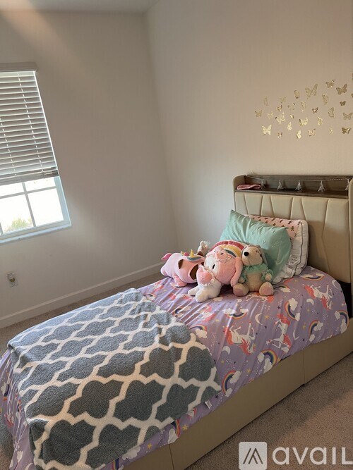 A bed with a blue and white patterned blanket and stuffed animals on it.