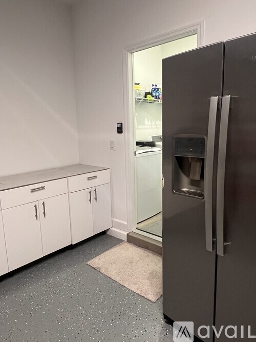 A kitchen with a black fridge and white cabinets.