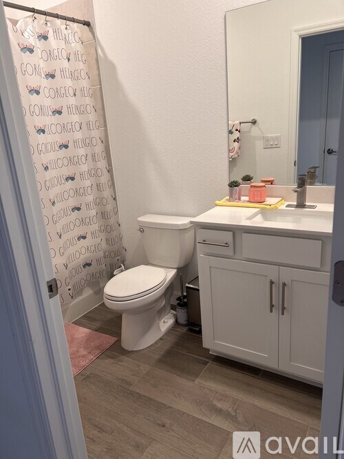 A bathroom with a toilet, sink, and a shower curtain with words on it.