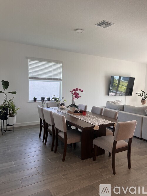 A dining room with a table set for six and a couch in the background.