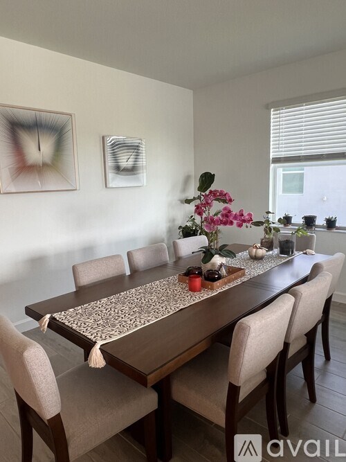 A dining table with chairs and a floral centerpiece.