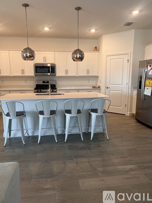 A kitchen with white chairs and a wooden floor.
