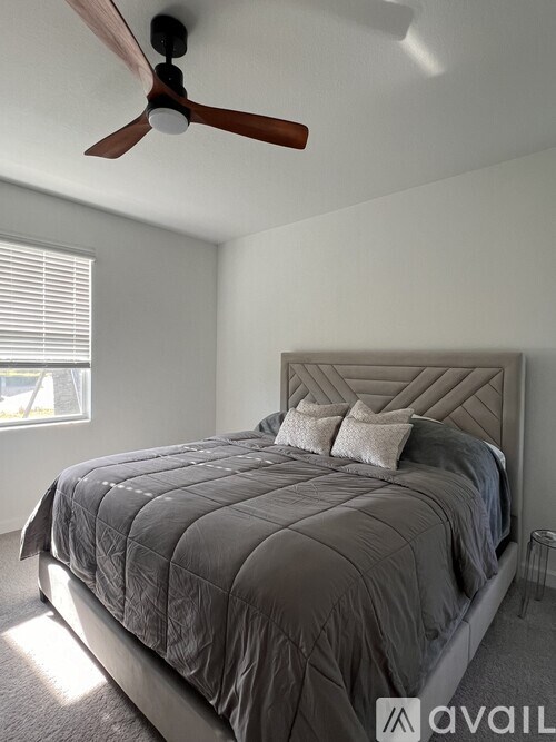 A bedroom with a bed, a ceiling fan, and a window with blinds.