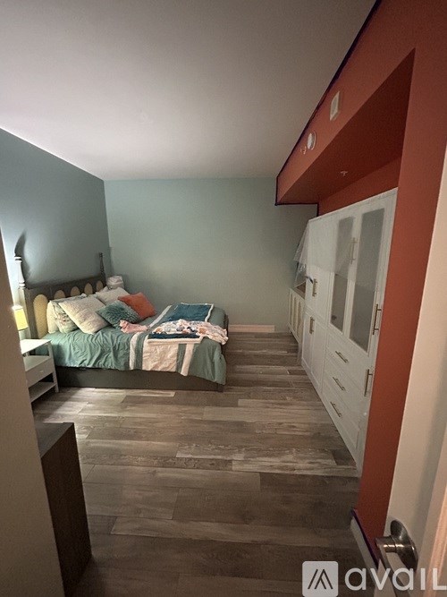 A bedroom with a bed and a wooden floor.