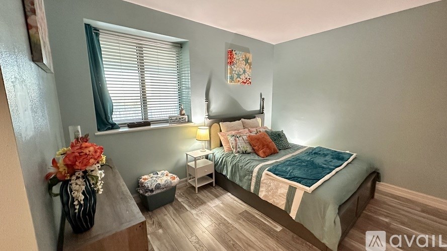 A bedroom with a bed, nightstand, and a vase of flowers.