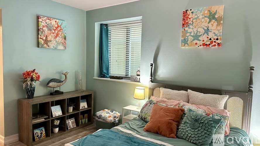 A bedroom with a bed, nightstand, and a shelf with vases and books.