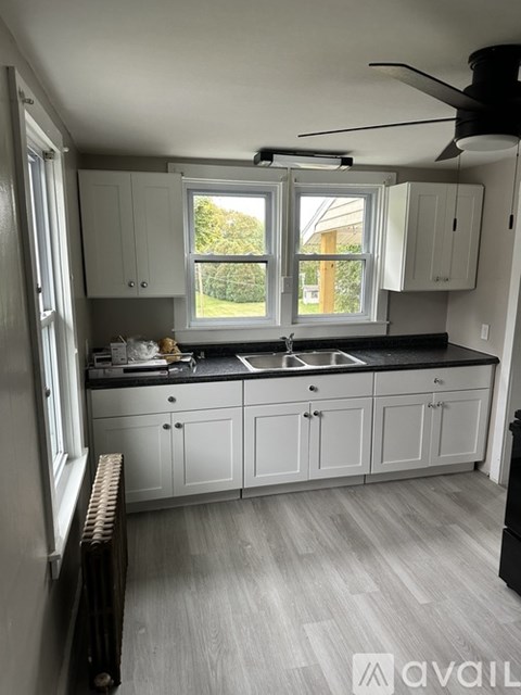 A kitchen with white cabinets and a black countertop.