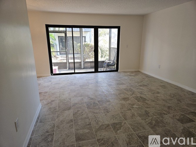A room with tiled flooring and a sliding glass door leading to a balcony.