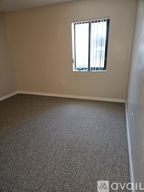 A room with a carpeted floor and a window with blinds.