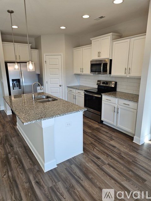 A kitchen with white cabinets and a granite countertop.