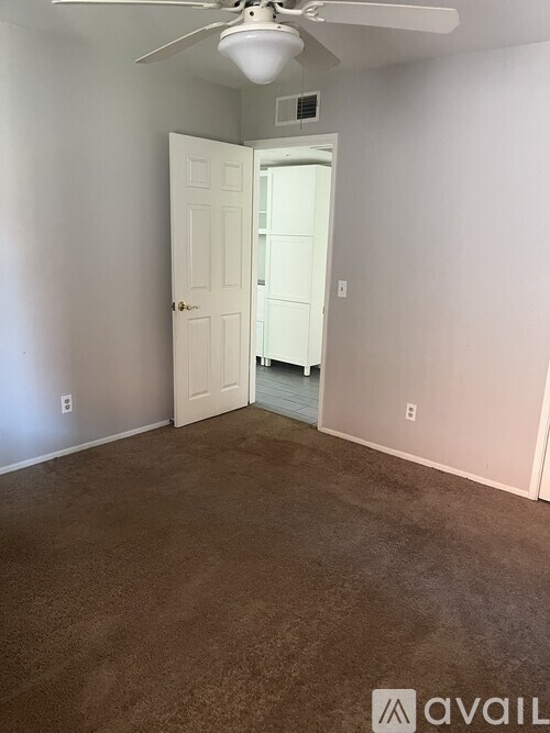 A room with a brown floor and a white ceiling fan.