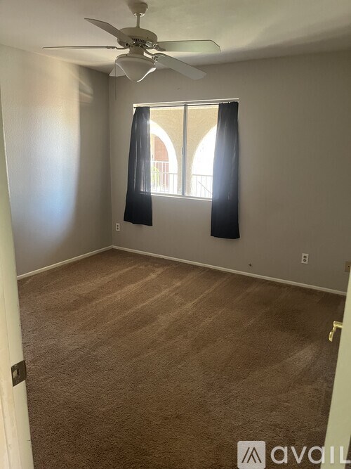 A room with a ceiling fan and carpeted floor.