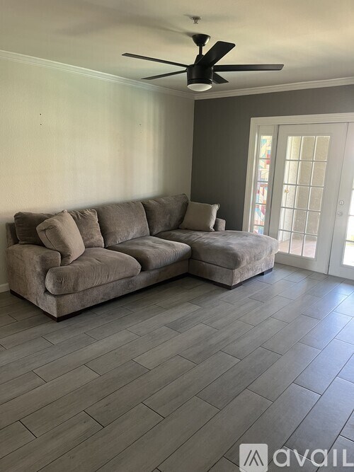 A living room with a grey sofa and a ceiling fan.