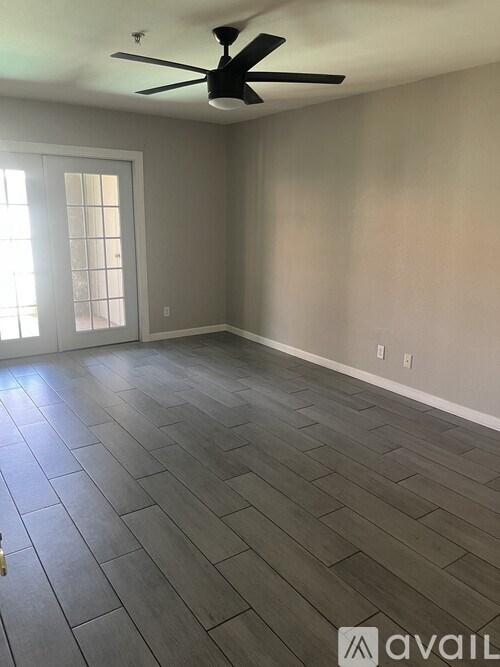 A room with a ceiling fan and wooden flooring.