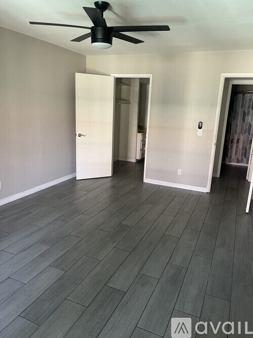 A room with a ceiling fan and wood flooring.