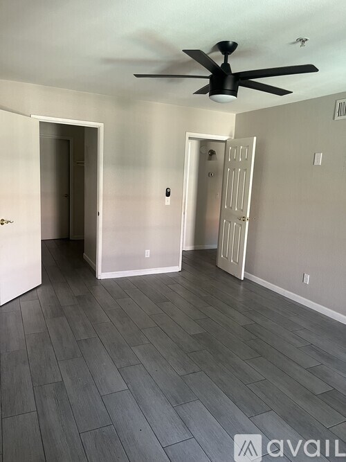 A room with a ceiling fan and wooden flooring.