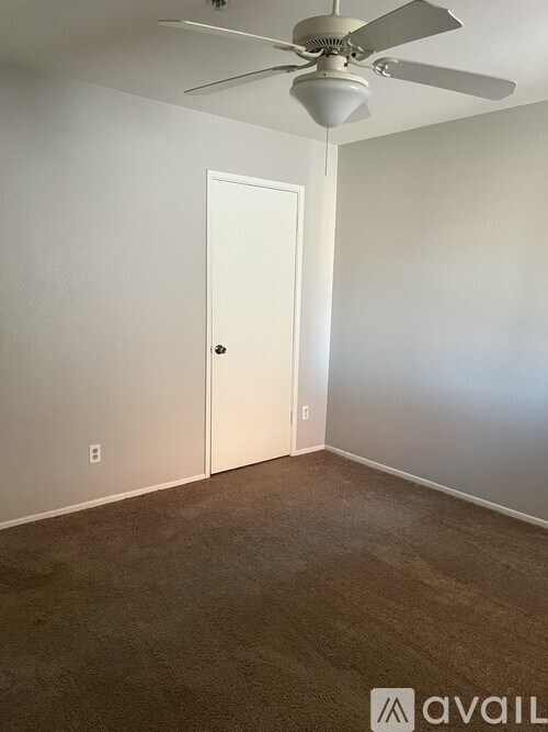A room with a white door and a ceiling fan.
