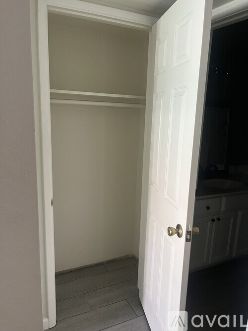 A white door with a gold handle is open to a dark room.