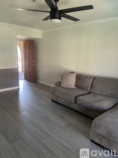 A living room with a grey couch and a ceiling fan.