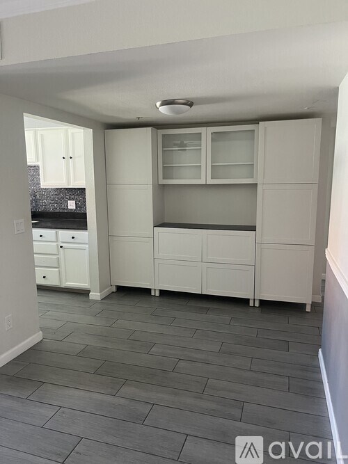 A kitchen with white cabinets and a tiled floor.