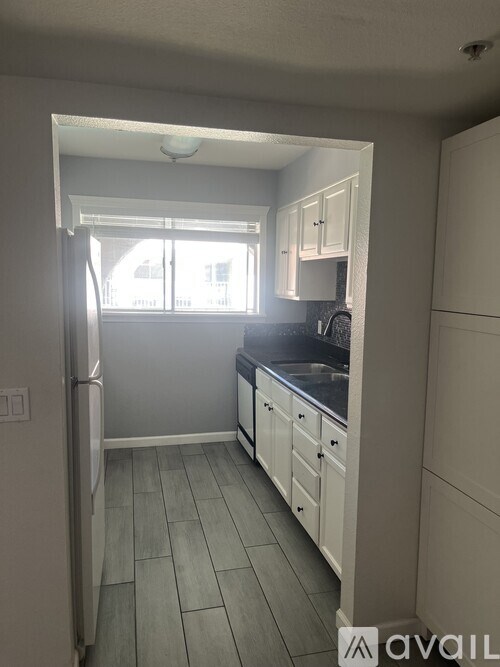 A kitchen with a refrigerator, cabinets, and a window.