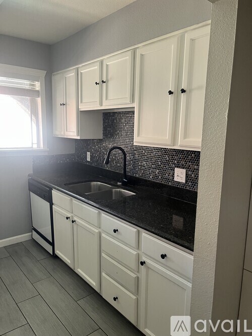 A kitchen with white cabinets and a black countertop.