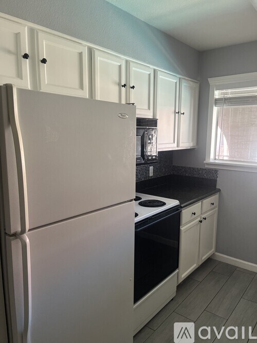 A kitchen with a white refrigerator and black countertops.
